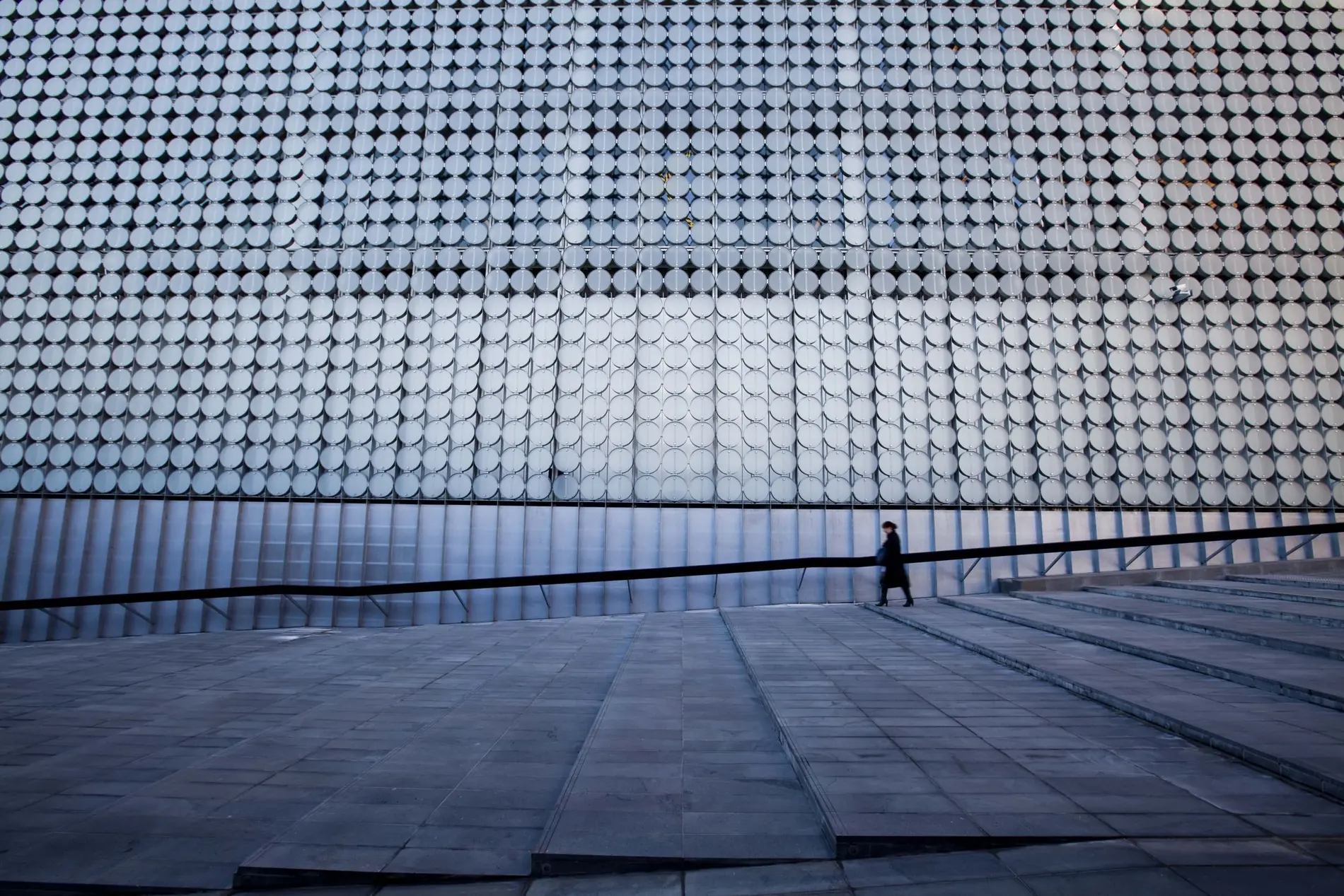 A solitary figure crossing a precisely ordered modern facade